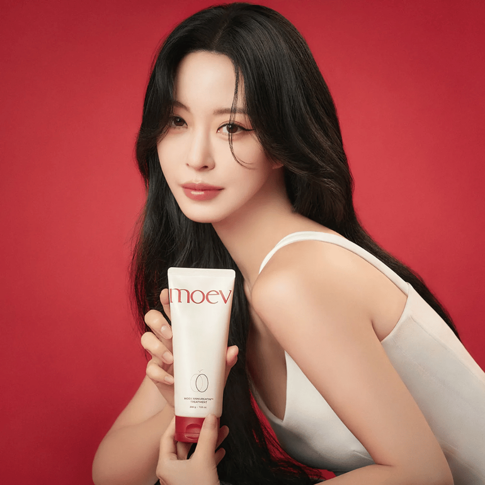Woman with long, shiny hair holds MOEV Annurcatin Treatment – Korean hair care that provides nourishment, strength, and shine with natural ingredients.