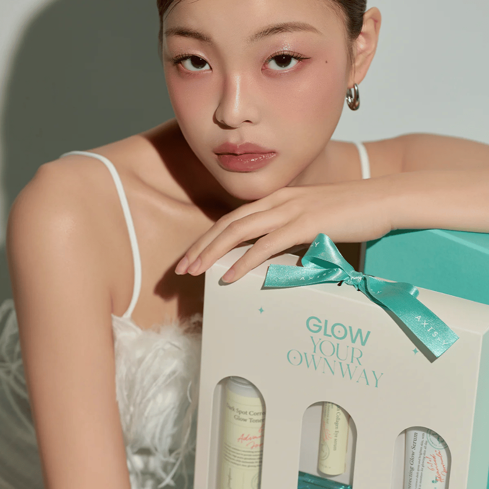 Model with elegant makeup holding AXIS-Y's “Glow Your Own Way” gift box – a stylish Skincare kit perfect as a gift for yourself or someone you care about.