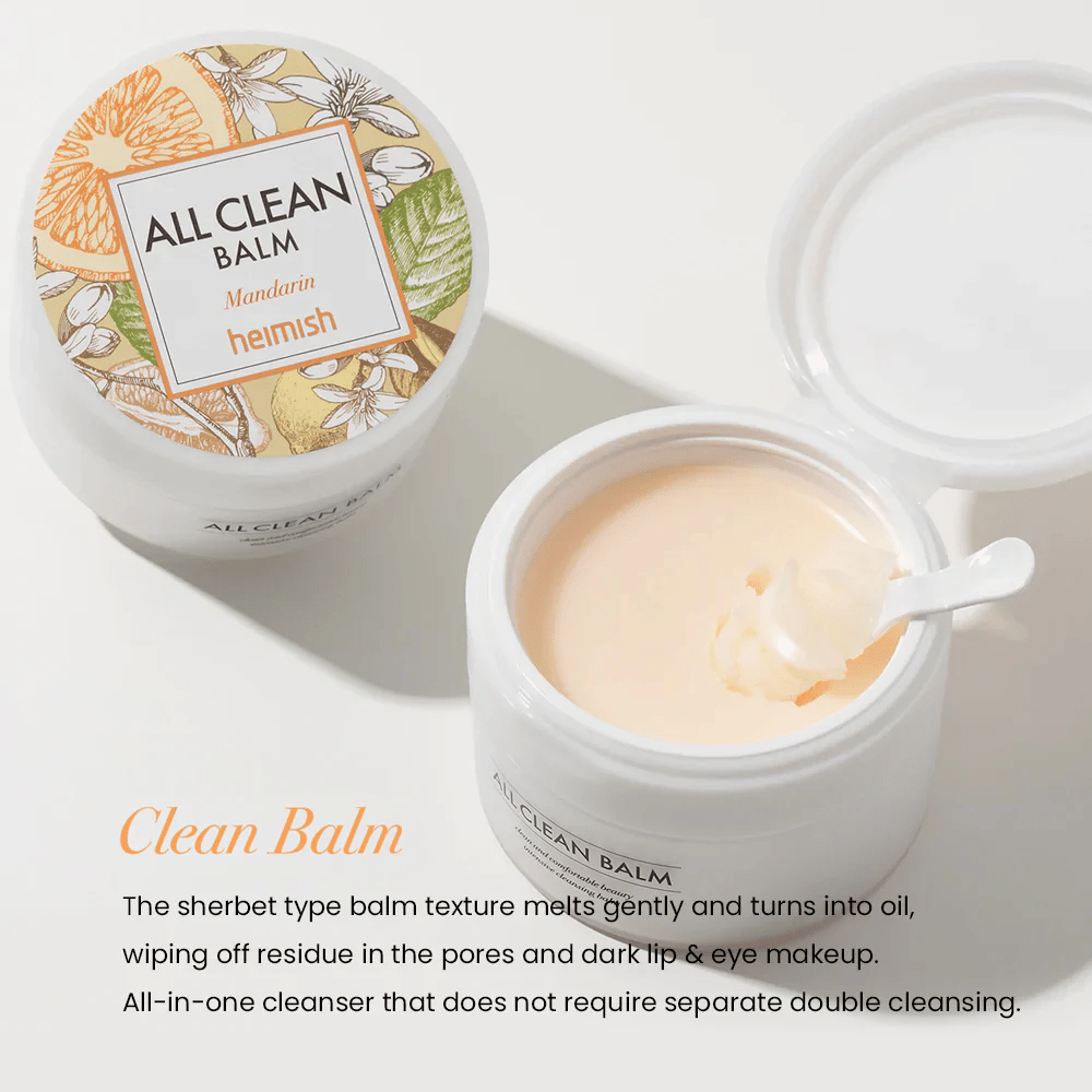 Open jar of Heimish All Clean Balm Mandarin with a spoon stirring the creamy cleansing balm, with a colorful label and the text 'Clean Balm' in the foreground.