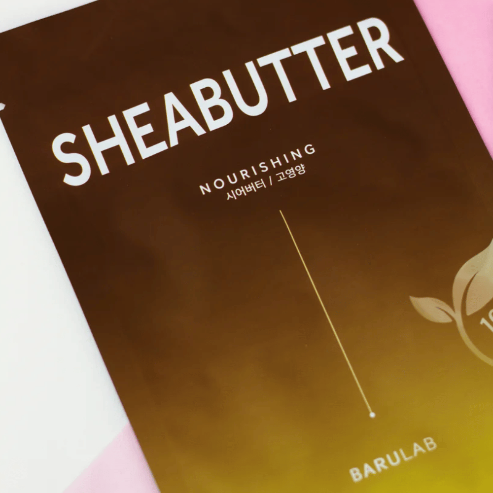 A close-up of a package of BARULAB "SHEABUTTER Nourishing" mask. The product is labeled as "100% Vegan Product" and has a color gradient from dark brown to light brown.