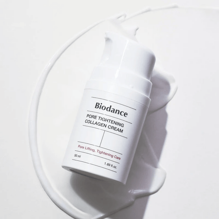 Biodance Pore Tightening Collagen Cream i vit pumpflaska, liggande på en swirl av vit kräm.