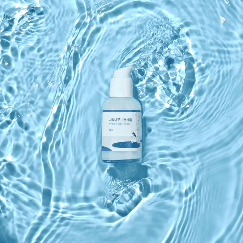 Round Lab Birch Juice Moisturizing Serum in a pump bottle floating on blue water with sunlight reflections.