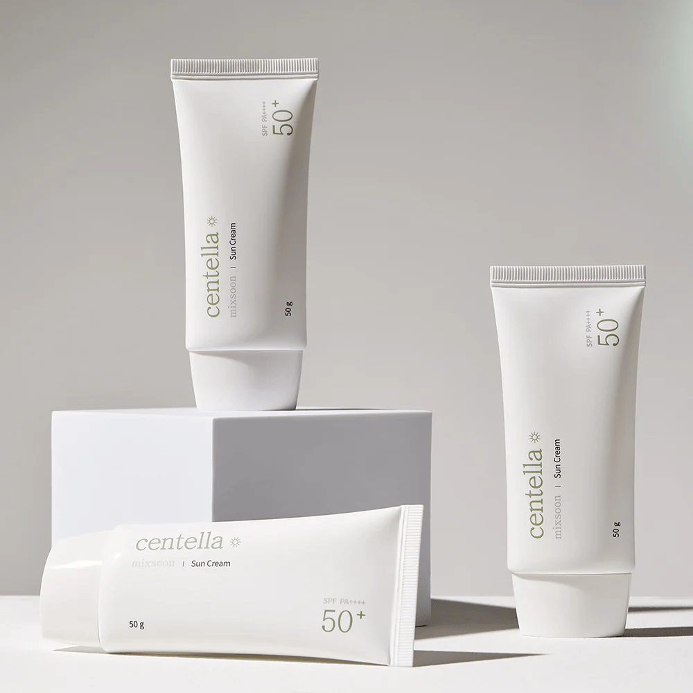 Three packages of Centella Sun Cream SPF 50+ PA++++ aesthetically arranged on white podiums. Two tubes are standing up and one is lying down, all with white, minimalist design and green text details.