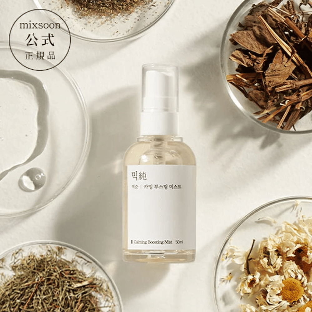 A transparent spray bottle with the label 'Calming Boosting Mist' from Mixsoon, surrounded by dried herbs and flowers on white bowls against a beige background, highlighting the products' natural ingredients.