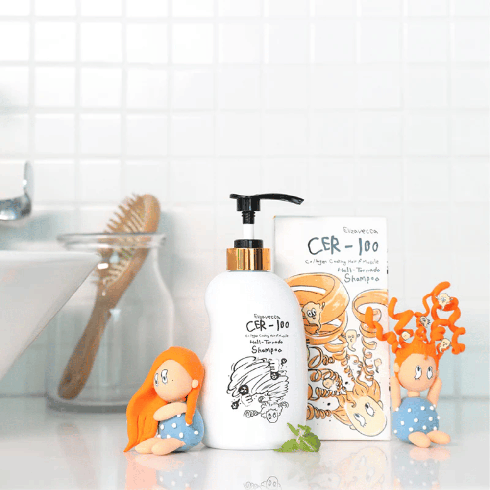 Elizavecca CER-100 Shampoo and box are shown in a bathroom setting next to a hairbrush and decorative figures. The image conveys an everyday hair care routine and the product's use in a home environment.