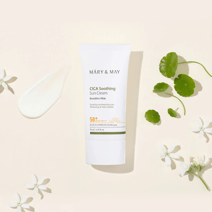 Mary&May CICA Soothing Sun Cream SPF50+ PA++++ presented together with a cream texture, centella leaves, and white flowers. The image highlights the product's soothing properties and focus on sensitive skin.