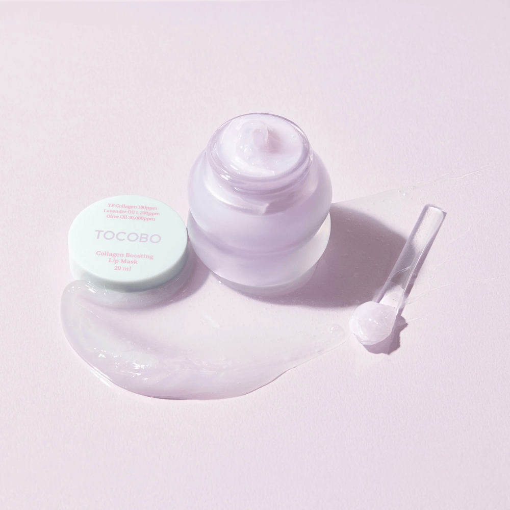 Open jar TOCOBO Collagen Boosting Lip Mask with a spatula and scattered purple cream on a light purple background.