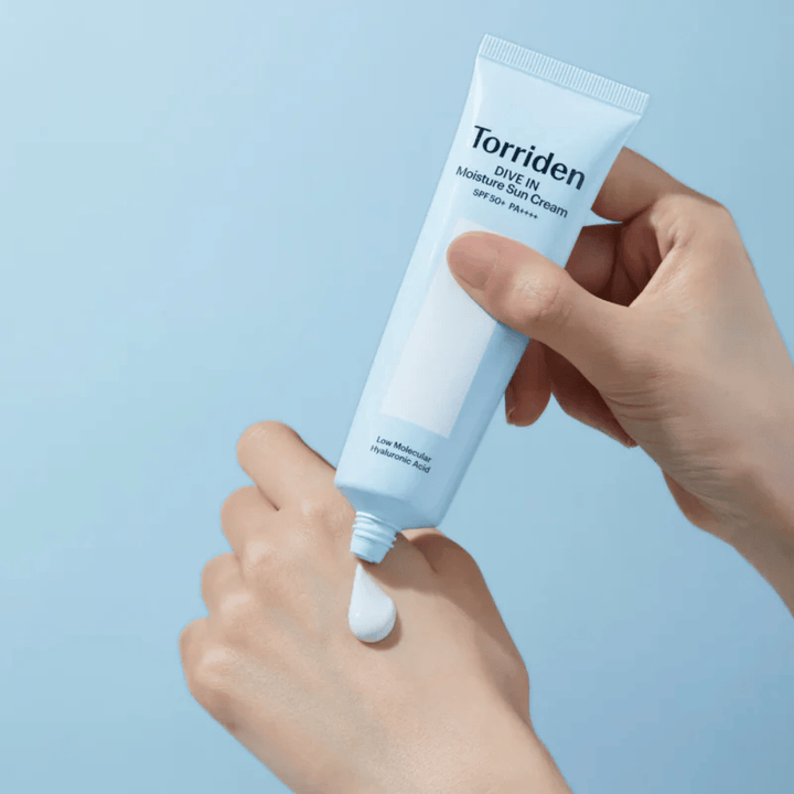 Torriden DIVE-IN Moisture Sun Cream SPF50+ PA++++ applied on the hand to show the light and creamy texture of the moisturizing sunscreen.