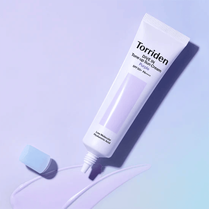 Open tube of Torriden DIVE IN Tone Up Sun Cream Purple with purple-tinted sunscreen texture showing the product's color-correcting formula.