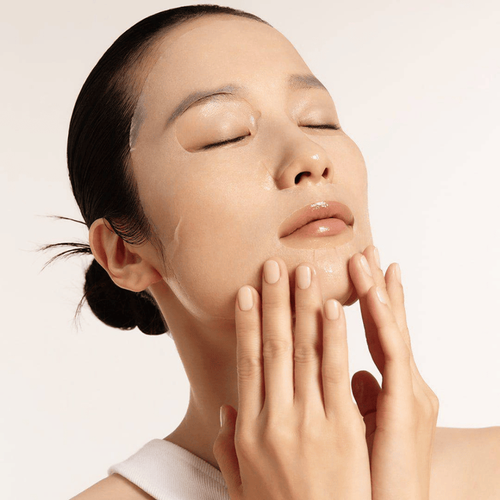 Model with hydrated and radiant skin applies Sheet mask, focus on radiance, even skin tone, and glow.