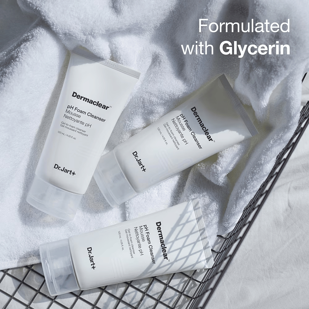 Three tubes of Dr.Jart+ Dermaclear pH Foam Cleanser lie on a white terry towel in a metal basket, with the text "Formulated with Glycerin" in the upper corner.