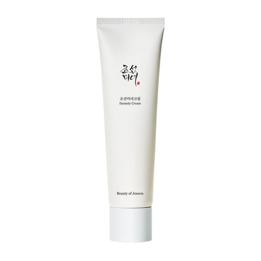 The image shows a tube of "Beauty of Joseon Dynasty Cream". The sleek, white tube has minimalist design elements, including elegant black and red text. This skincare product promises to nourish and revitalize the skin, reflecting the historical beauty secrets from the Joseon dynasty.