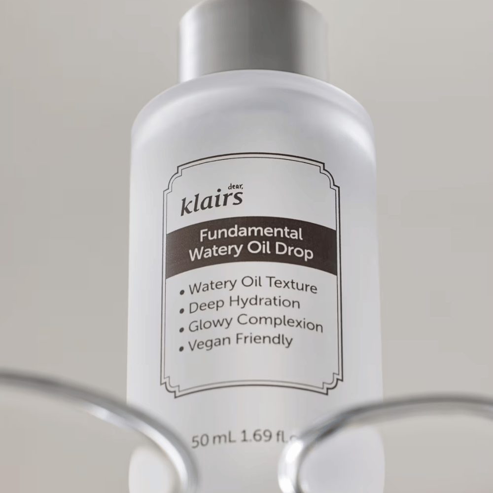 Bottle with Klairs Fundamental Watery Oil Drop, 50 ml, placed in a transparent holder, with a clear label highlighting the product's moisturizing and vegan properties.