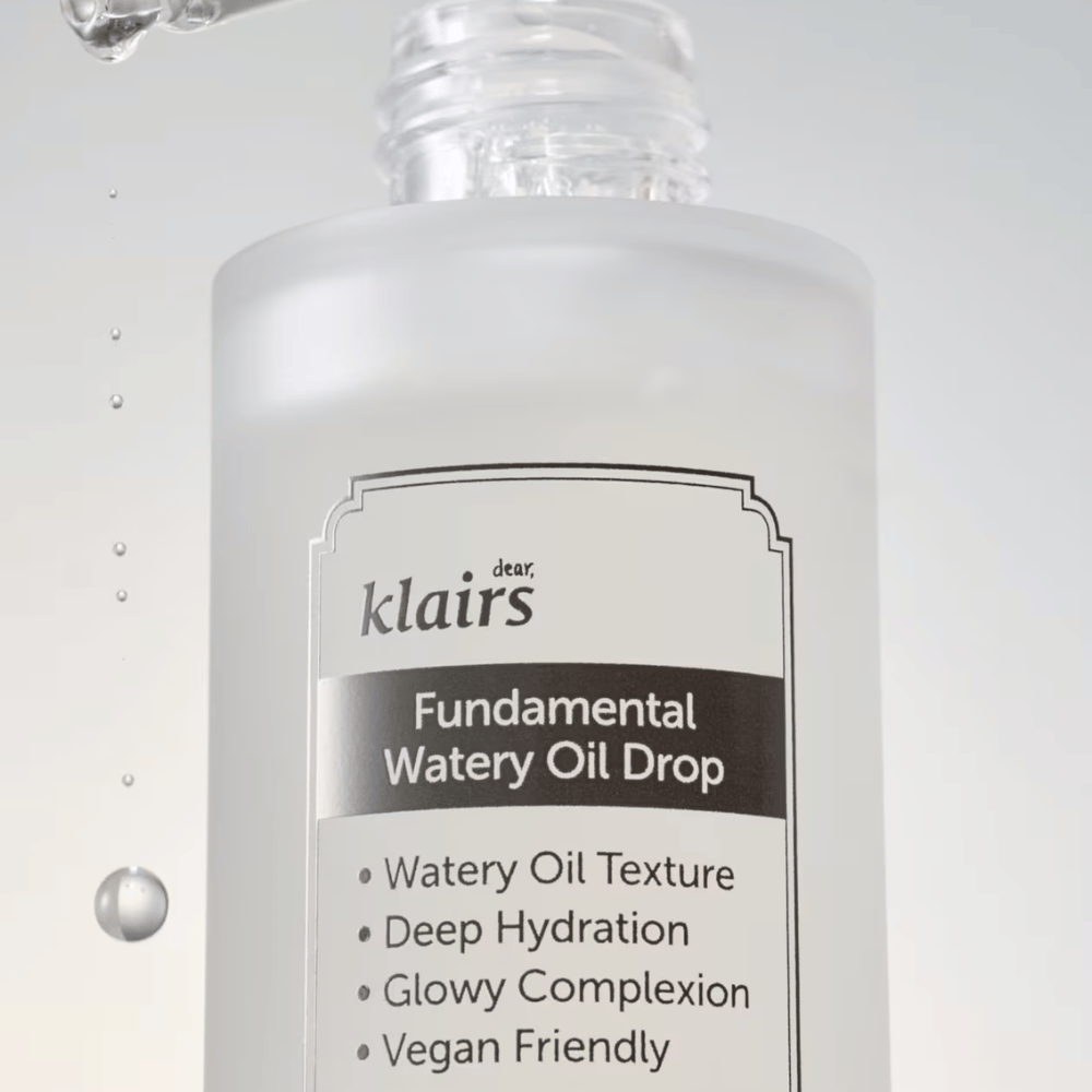 Close-up of the bottle Klairs Fundamental Watery Oil Drop, with text highlighting the product's properties such as "Watery Oil Texture", "Deep Hydration", "Glowy Complexion", and "Vegan Friendly".