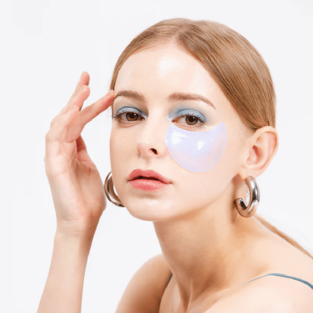 Model wears a blue shimmering hydrogel eye patch under the eye for a refreshing effect.