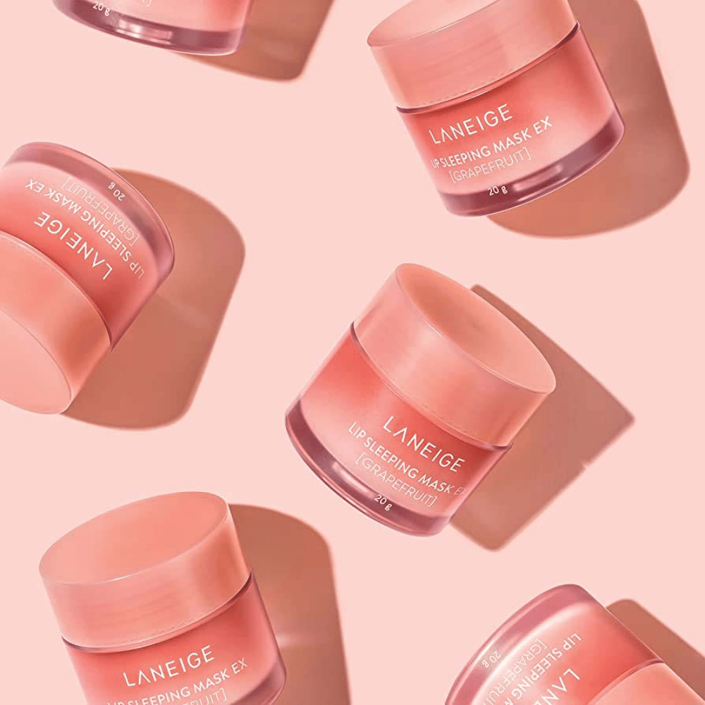 Four jars LANEIGE Lip Sleeping Mask Grapefruit 20g on a pink background, promoting grapefruit and moisturizing.