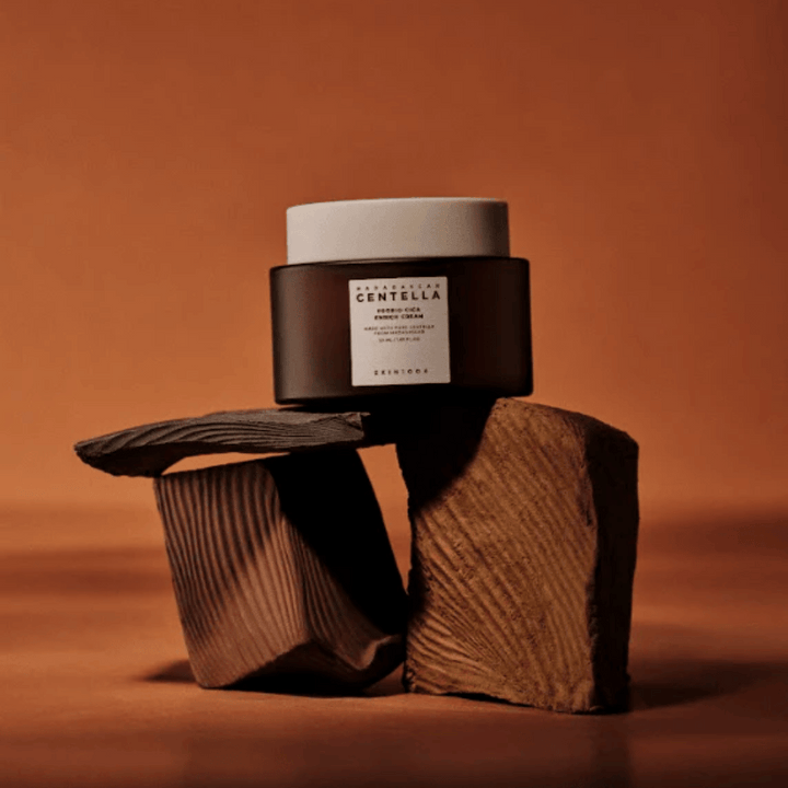 SKIN1004 Madagascar Centella Probio-Cica Enrich Cream i elegant brun glasburk på dekorativa träblock – näringsrik koreansk ansiktskräm som stärker hudbarriären.