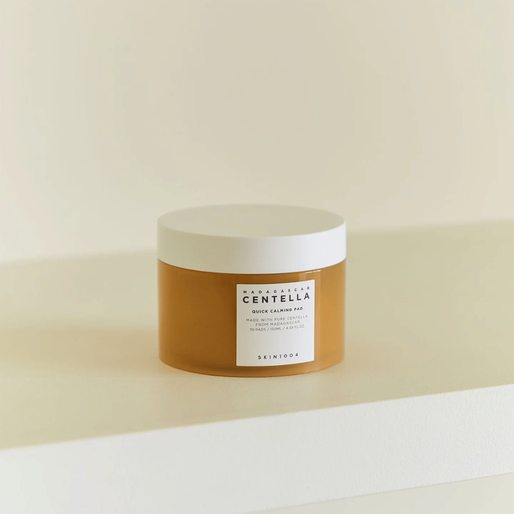 SKIN1004 Madagascar Centella Quick Calming Pad placed on white shelf – amber-colored jar with white lid and prominent label on the front.