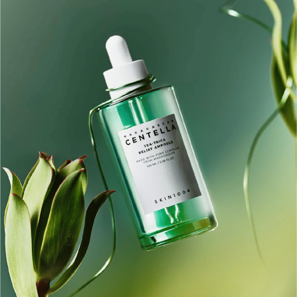SKIN1004 Madagascar Centella Tea-Trica Relief Ampoule – green glass bottle with pipette, white label and 100 ml content, photographed against a green background with plant details.