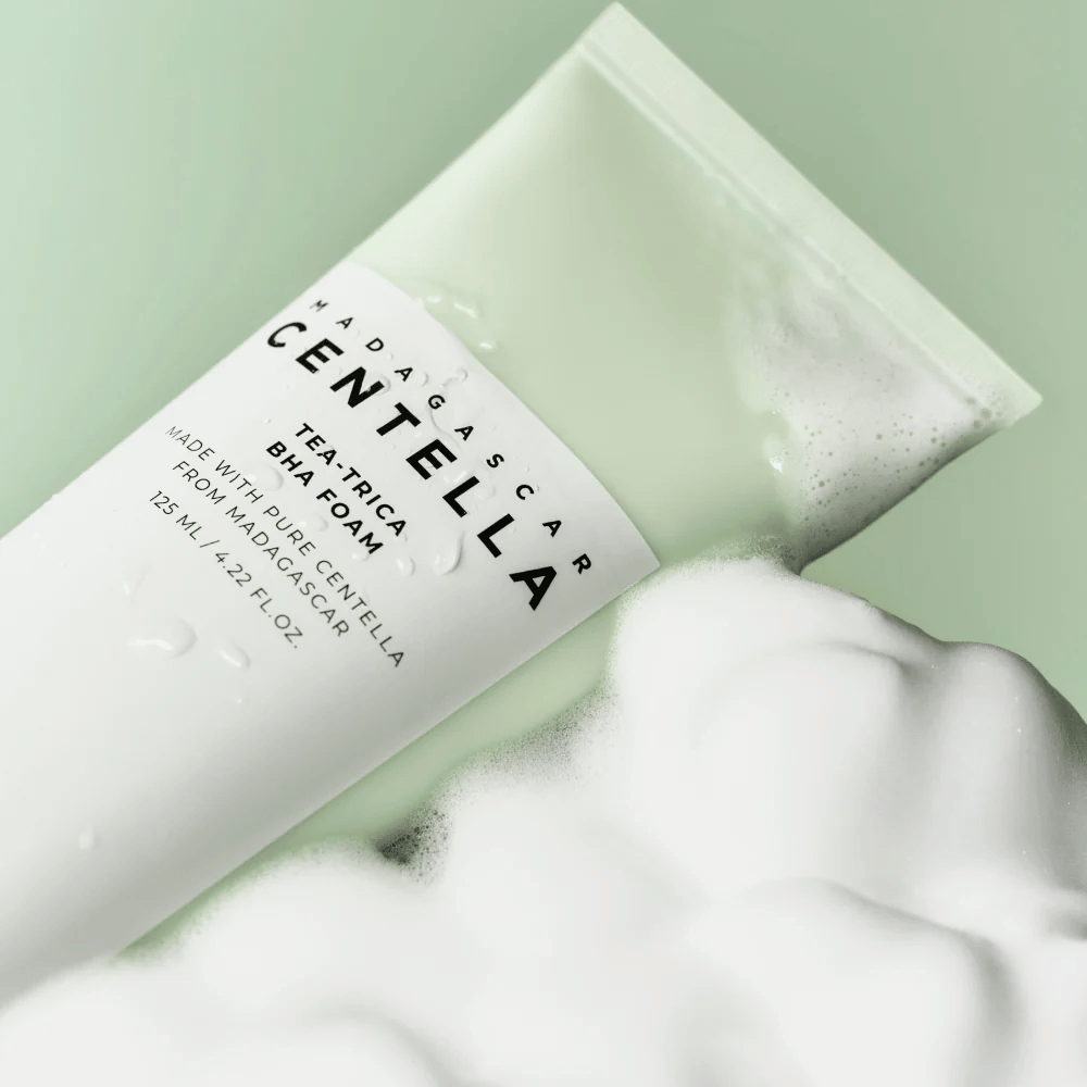 A product of the type cleansing foam, "Madagascar Centella Tea-trica BHA Foam," is partially visible with foam around it. The product has a green and white design, and the text "Madagascar Centella" and "Tea-trica BHA Foam" are clearly visible. The volume is 125 ml.