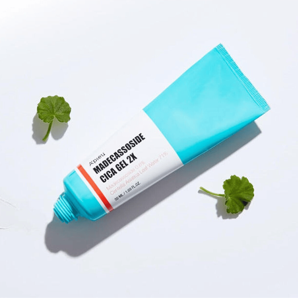 A'pieu Madecassoside Cica Gel 2X in a blue tube with a white label, surrounded by three green centella asiatica leaves on a white background.