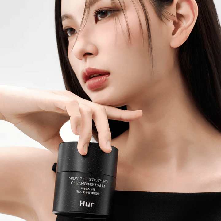 Model holds How Midnight Soothing Cleansing Balm. Korean cleansing balm that effectively removes makeup and cleanses the skin without irritation.