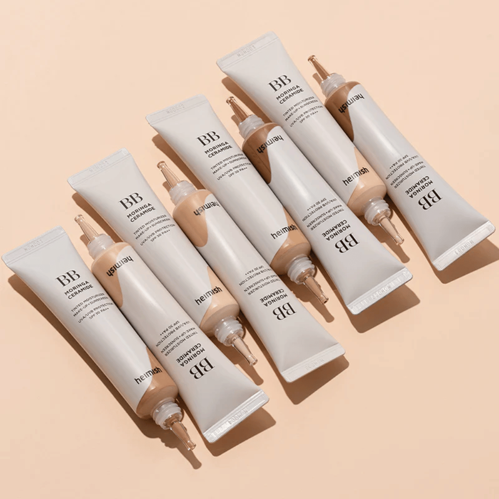 Several tubes of Heimish Moringa Ceramide BB Cream arranged on a light beige background. The image highlights the different shades and the product's elegant, minimalist packaging design.