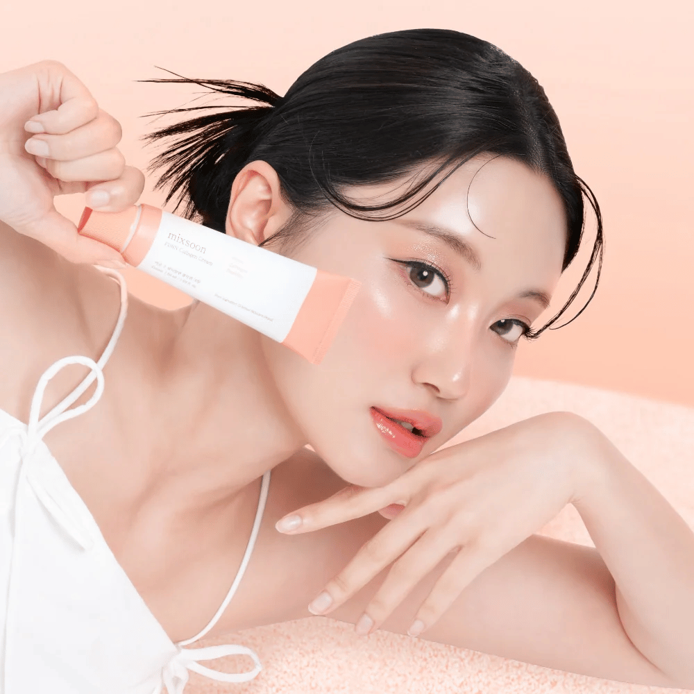Person with radiant skin holds Mixsoon PDRN Collagen Cream close to the cheek. The cream moisturizes, strengthens elasticity, and gives a healthy glow.