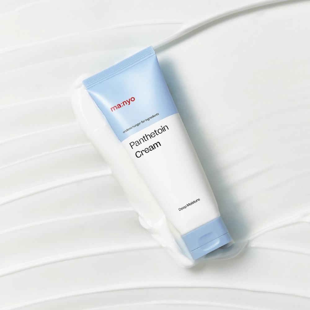 2. Ma:nyo Panthetoin Cream – moisturizing face cream in a white and light blue tube surrounded by a creamy texture on a white background