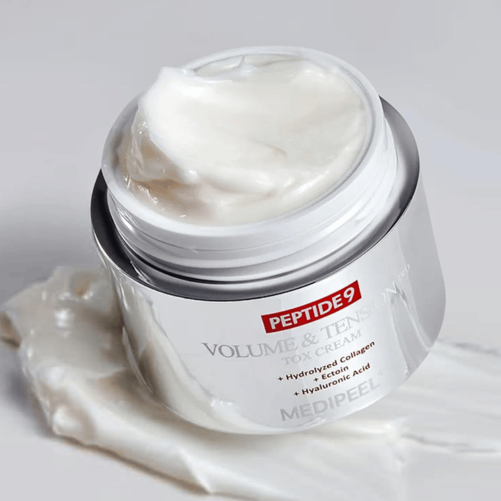 Närbild på MEDI-PEEL Peptide 9 Volume & Tension Tox Cream. Den rika krämen innehåller hydrolyserat kollagen, ectoin och hyaluronsyra för fastare och återfuktad hud.