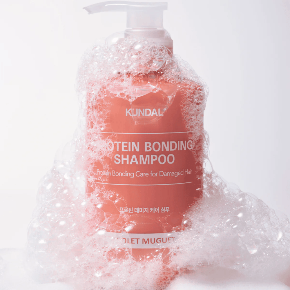 KUNDAL Protein Bonding Shampoo Violet Muguet covered by rich foam, repairing shampoo for damaged hair.