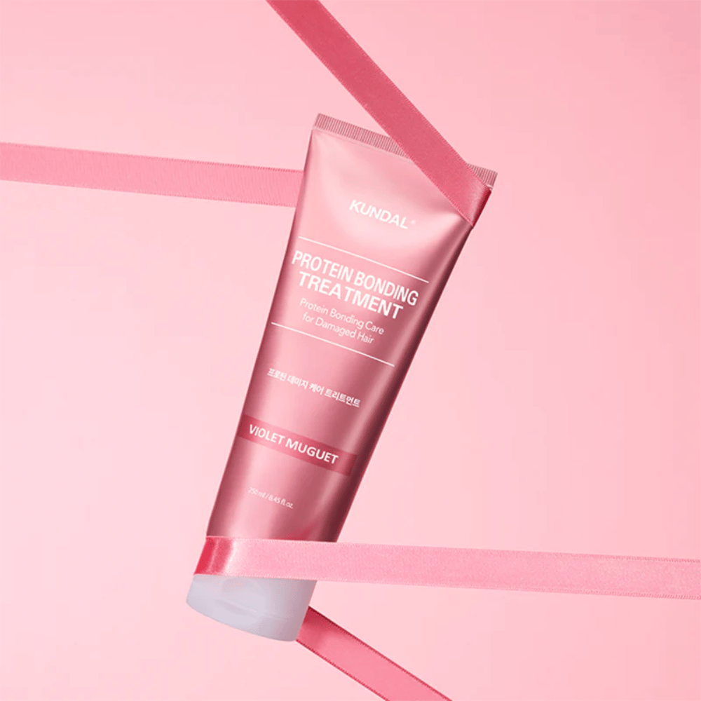 KUNDAL Protein Bonding Treatment Violet Muguet in pink tube 250 ml against pink background with decorative ribbons.