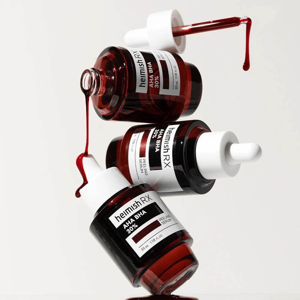 Three bottles of Heimish RX AHA BHA 30% Peeling Serum in a dynamic composition, with red-colored serum dripping from the droppers.