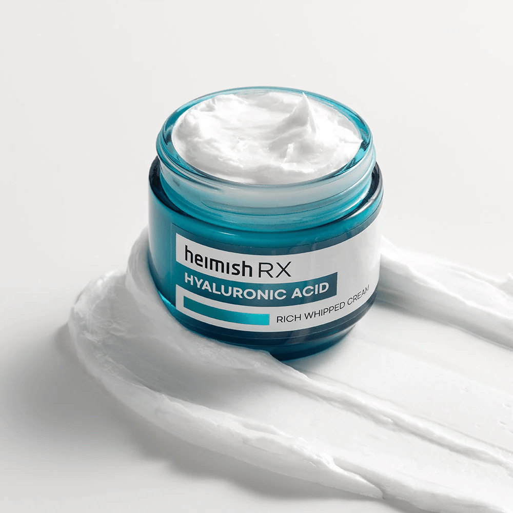 Heimish RX Hyaluronic Acid Rich Whipped Cream in a blue glass jar with a rich and fluffy texture, spread on a white background. Intensely moisturizing face cream with hyaluronic acid for deep hydration and soft skin.