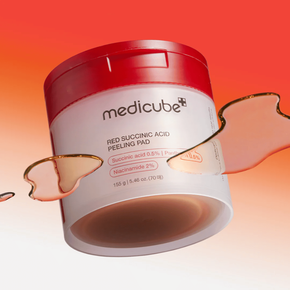 Medicube Red Succinic Acid Peeling Pad in a white and red jar, placed against a gradient background in red and orange. The product contains succinic acid and niacinamide for exfoliation and skin improvement. Liquid texture is visible around the jar.