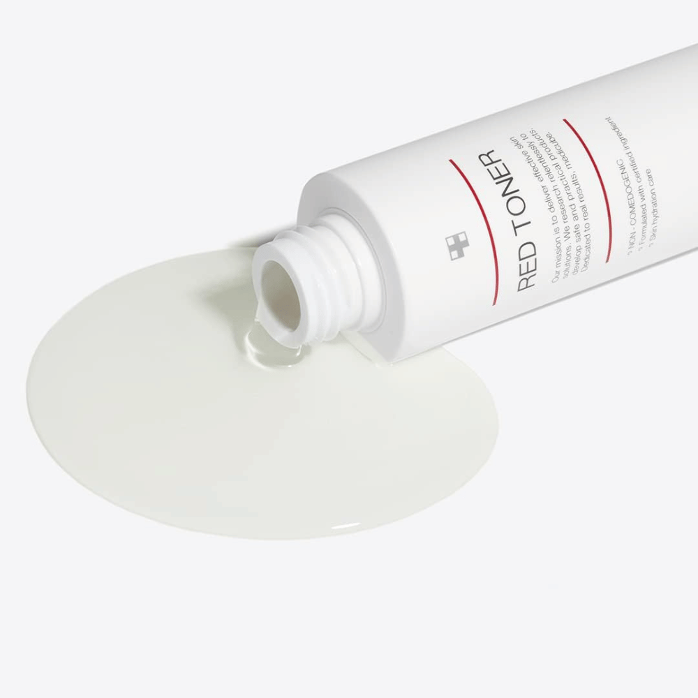 Open bottle with medicube Red Toner being poured onto a white surface – showing the product's light and liquid consistency.