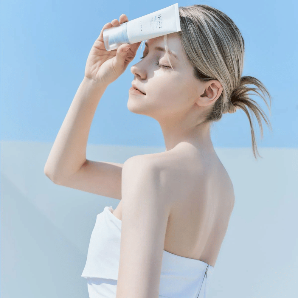 A woman applies SKIN1004 Madagascar Centella Hyalu-Cica Water-Fit Sun Serum 50ml to protect her face from UV rays.