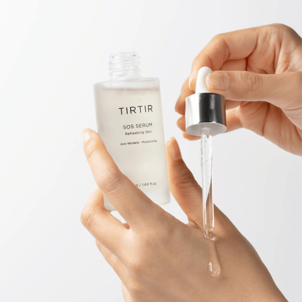 Hands dripping TIRTIR SOS Serum from a pipette, intended for skincare.