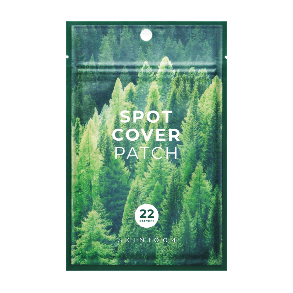Packaging with "Spot Cover Patch" containing 22 patches, designed with a green forest motif. The text "SPOT COVER PATCH" is printed in white on the front, and a circle marks the number of patches. The product is from the brand SKIN1004.