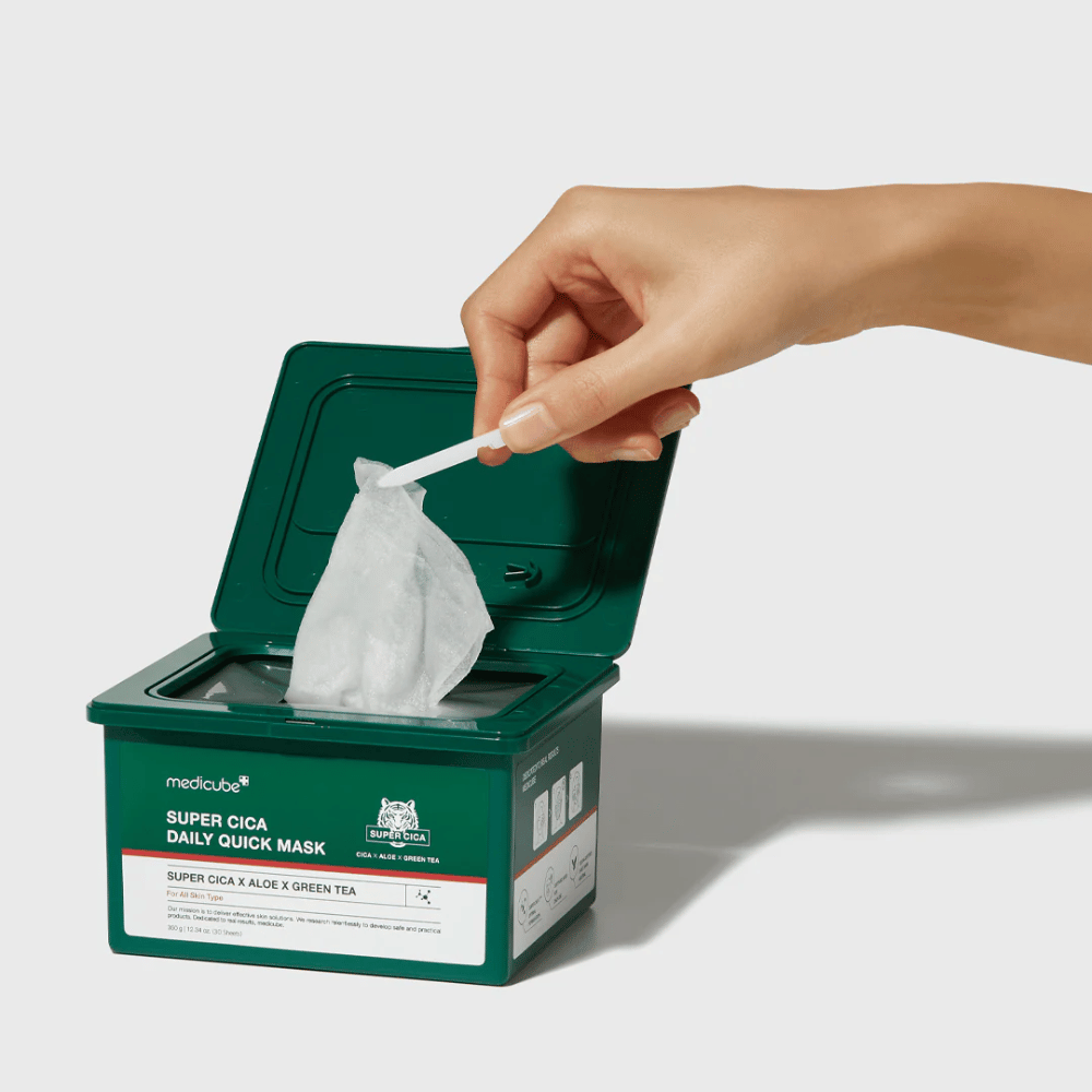 Green container with open lid shows medicube Super Cica Daily Quick Mask. A hand pulls up a sheet mask with the included tweezers. The product contains Cica, aloe, and green tea, ideal for quick hydration and soothing effect.