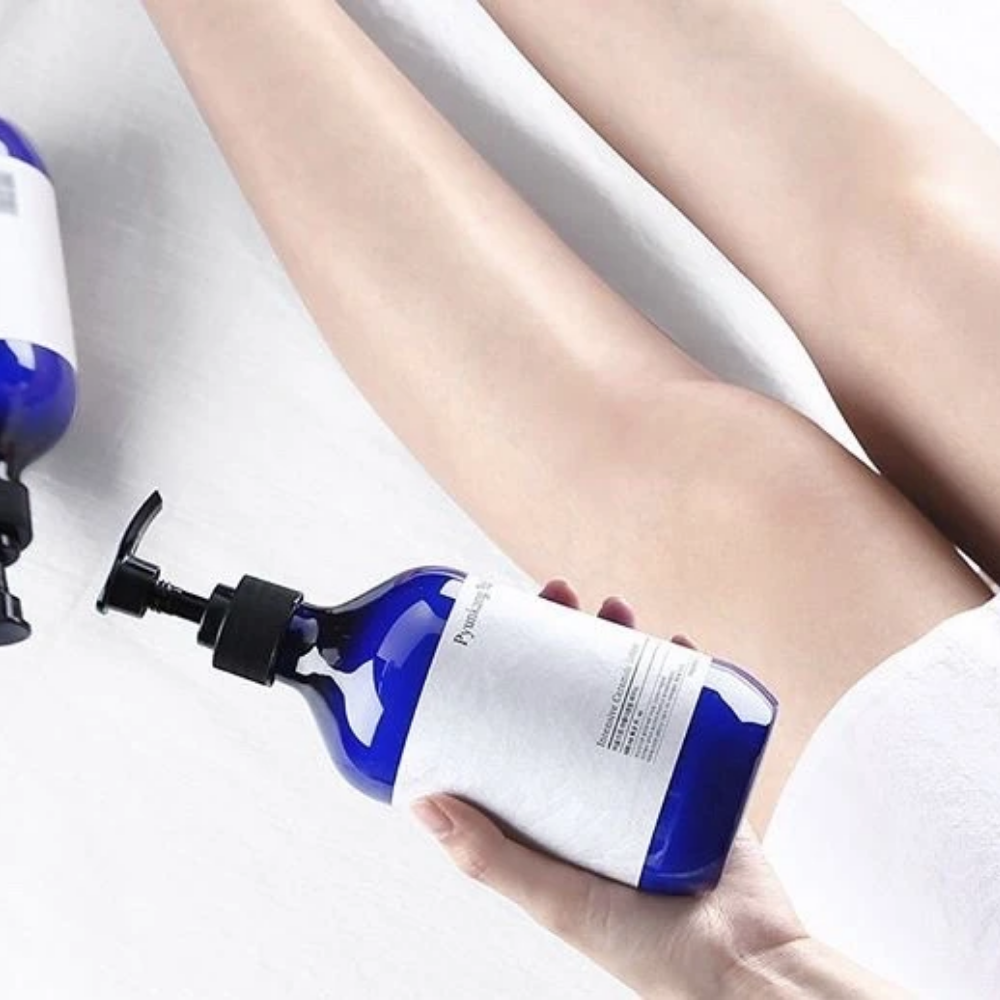 A woman holding a bottle Pyunkang Yul Intensive Ceramide Lotion 500ml next to her legs.