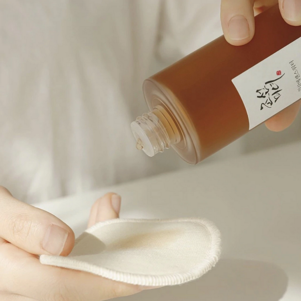 A person pouring Beauty of Joseon Ginseng Essence Water 150ml on a cloth to address dry skin and reduce sebum production.