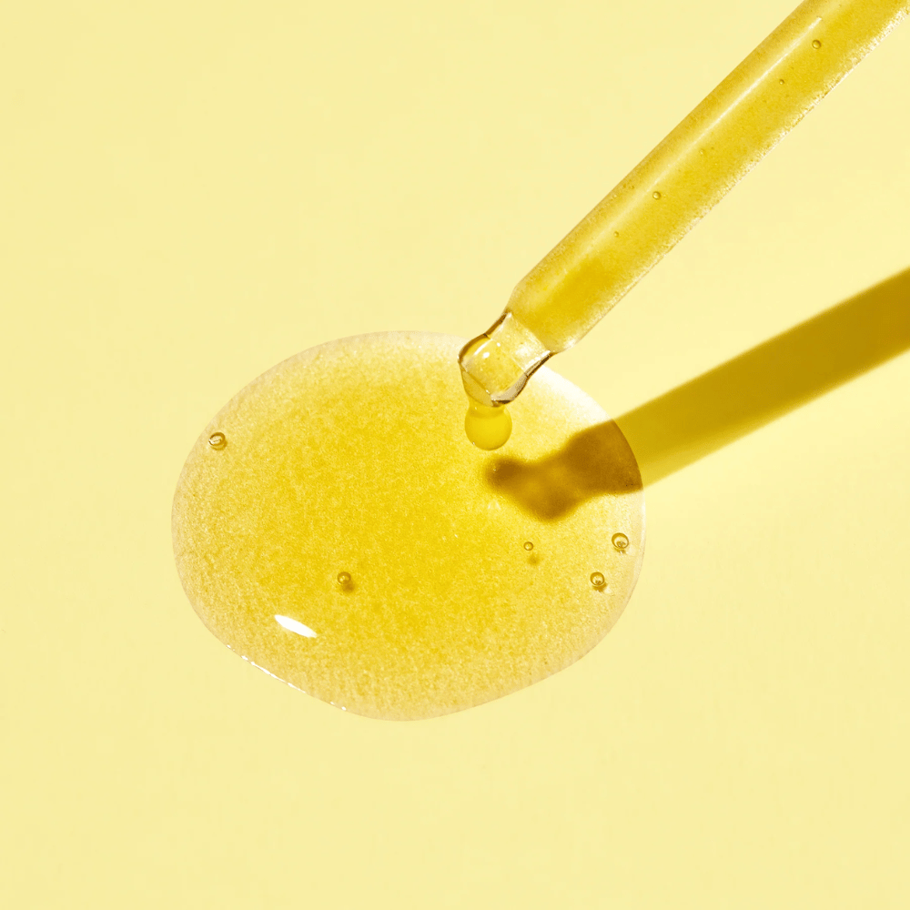 A drop of liquid on a yellow background, with MISSHAs Vita C Plus Spot Correcting & Firming Ampoule.